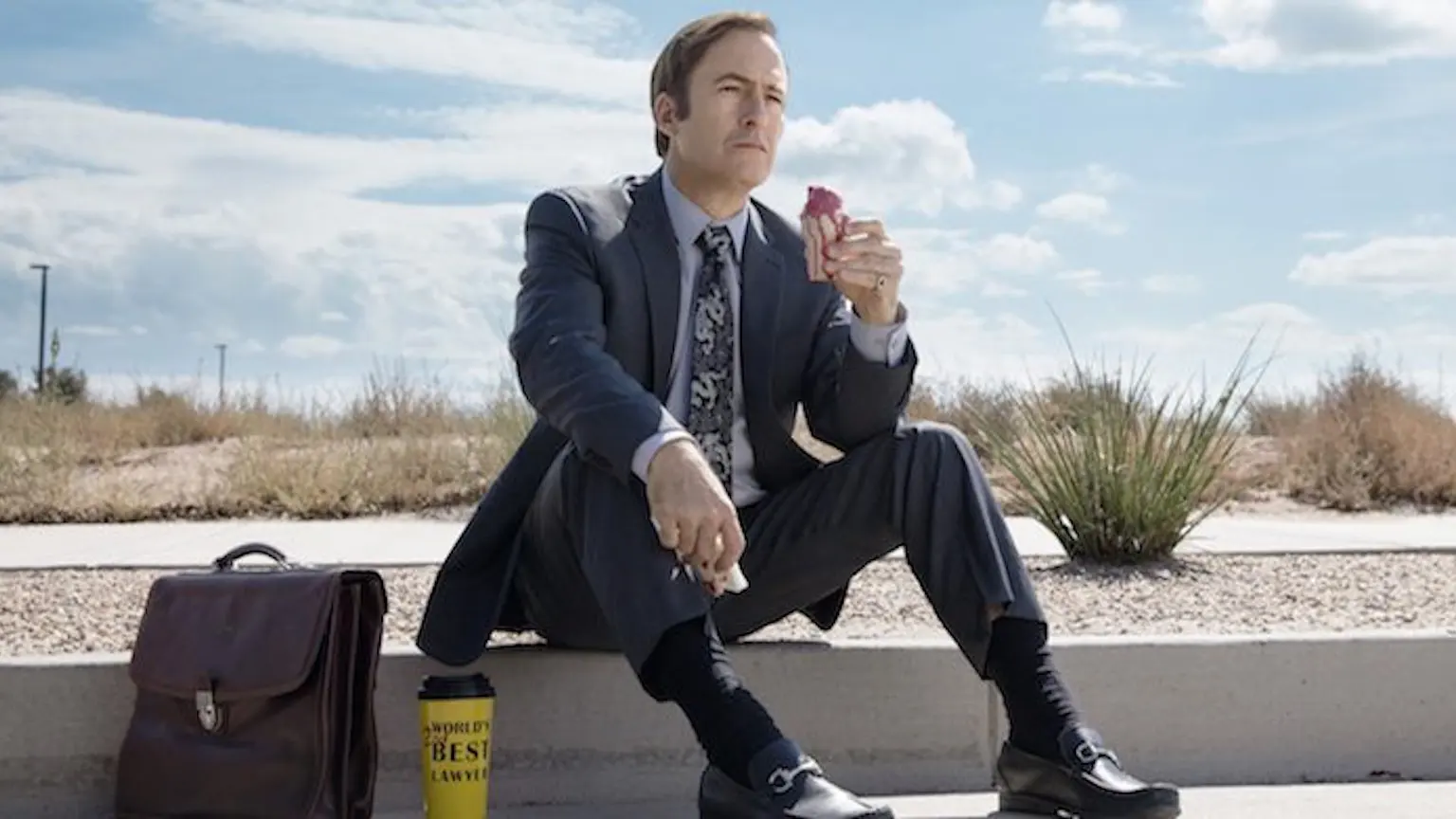 Saul Goodman, sitting on the gutter with his briefcase and coffee eating a donut
