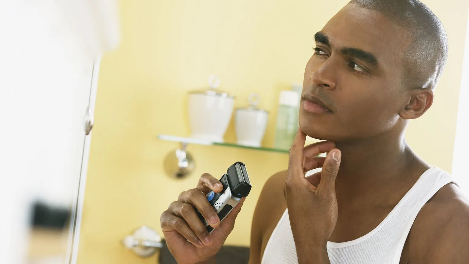 Close up of a man shaving his beard with an electric shaver.