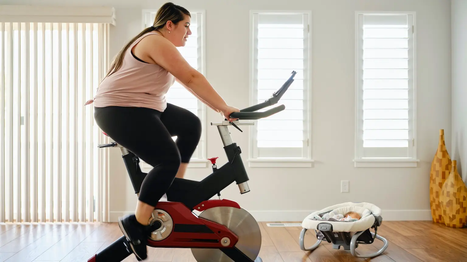 A young mother exercising in her home on an exercise bike.