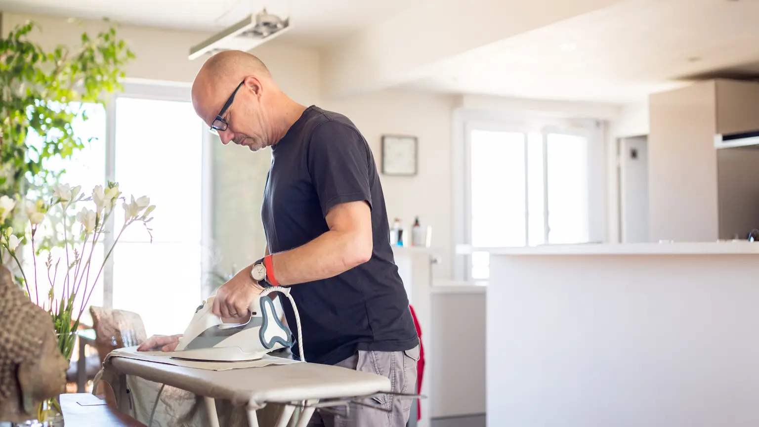 Man using an iron on an ironing board at home