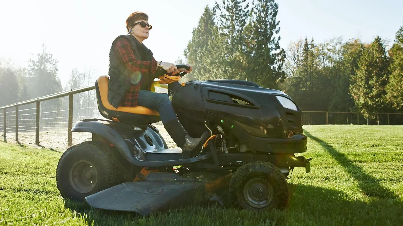 Shot of a mature woman driving a lawnmower on a farm