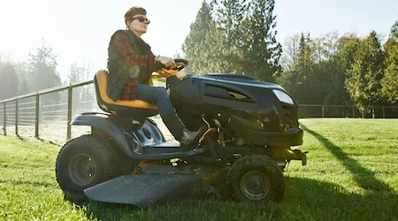 Shot of a mature woman driving a lawnmower on a farm