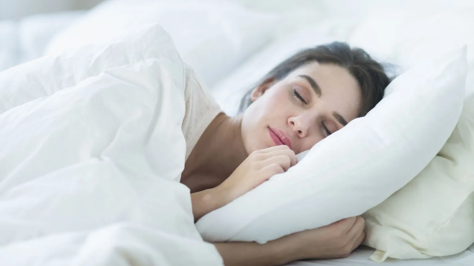 Woman sleeping comfortably on soft white pillows