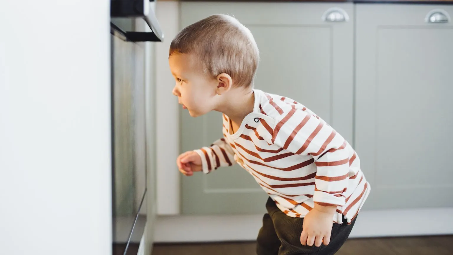 Little boy peering into an oven