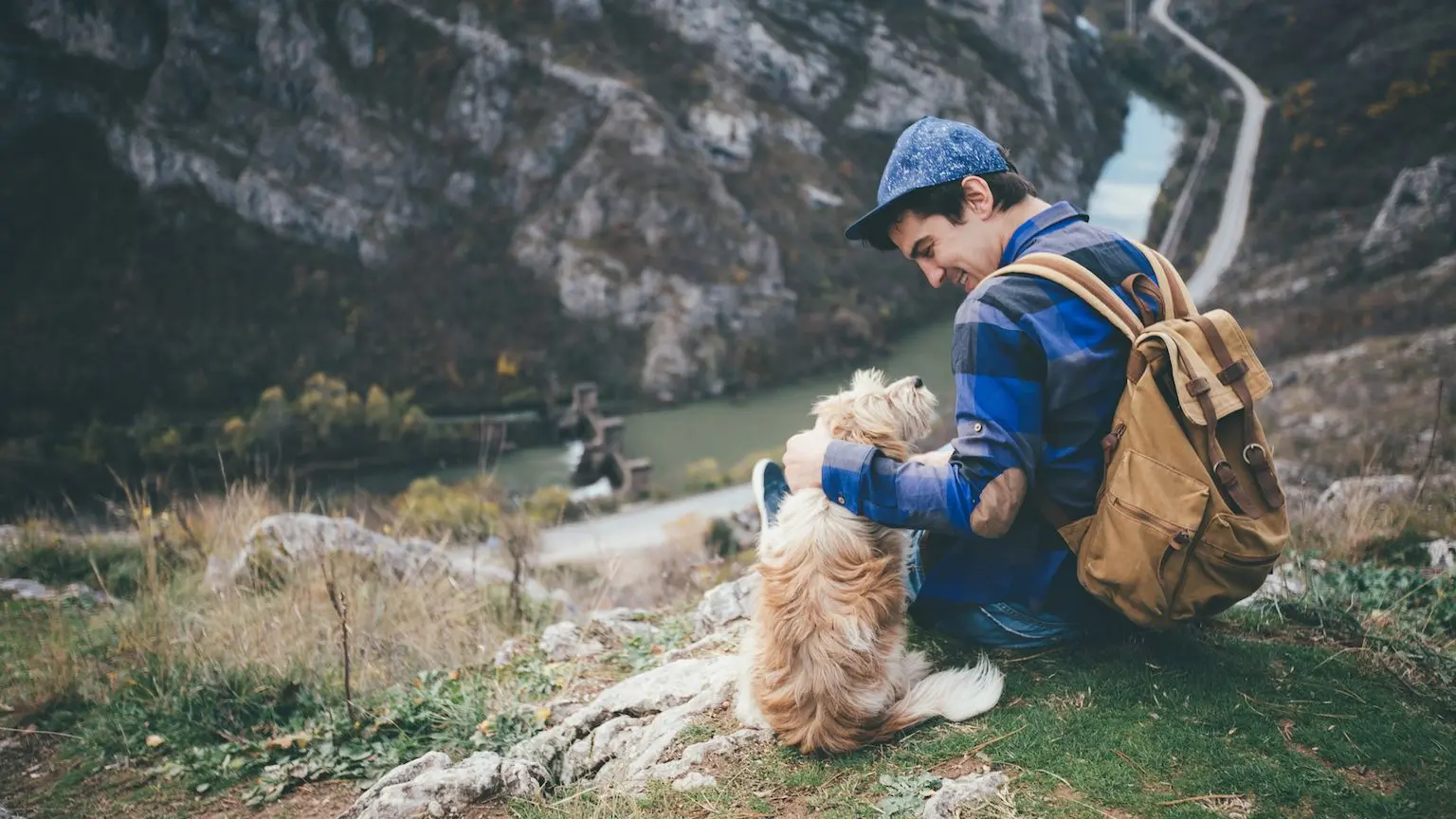 Man wearing a backpack taking his dog on a hike