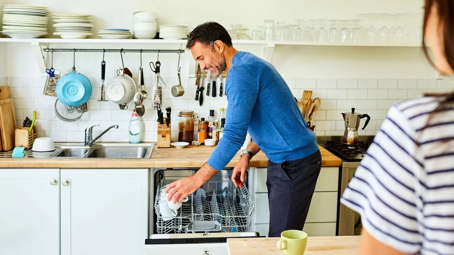 A man loading a dishwasher in his kitchen.