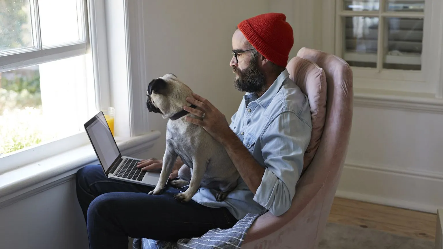 Man using a laptop with his dog sitting on his lap