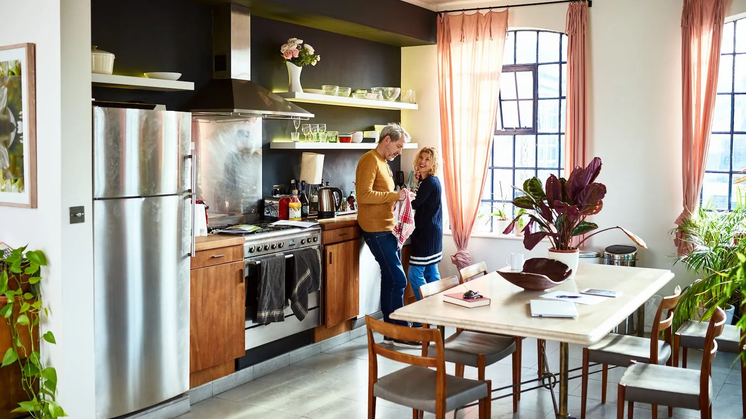 A man and woman laughing in their brightly lit kitchen