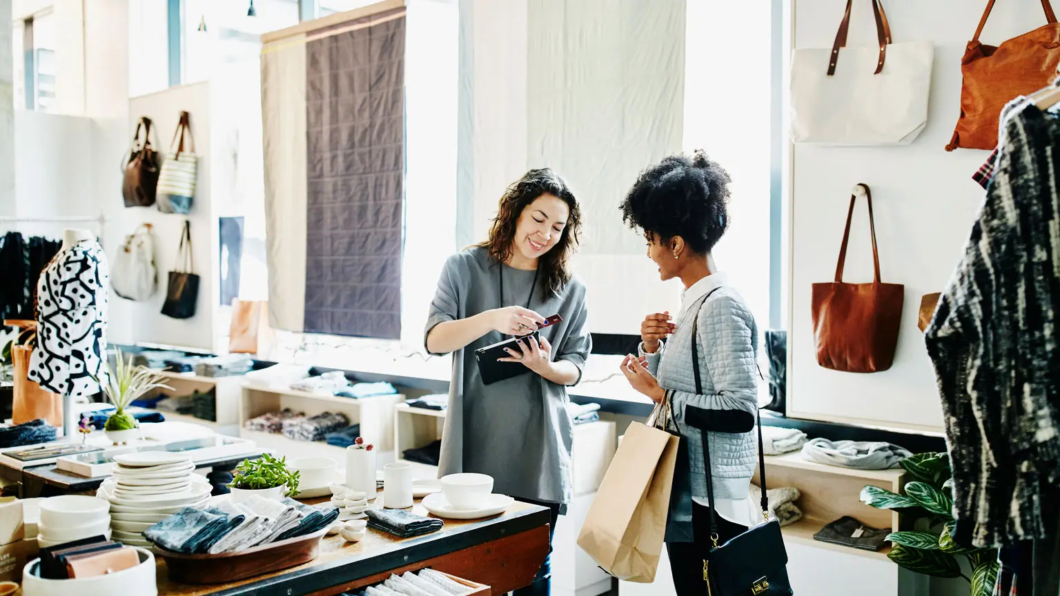 Smiling shop owner using digital tablet to process credit card transaction with customer