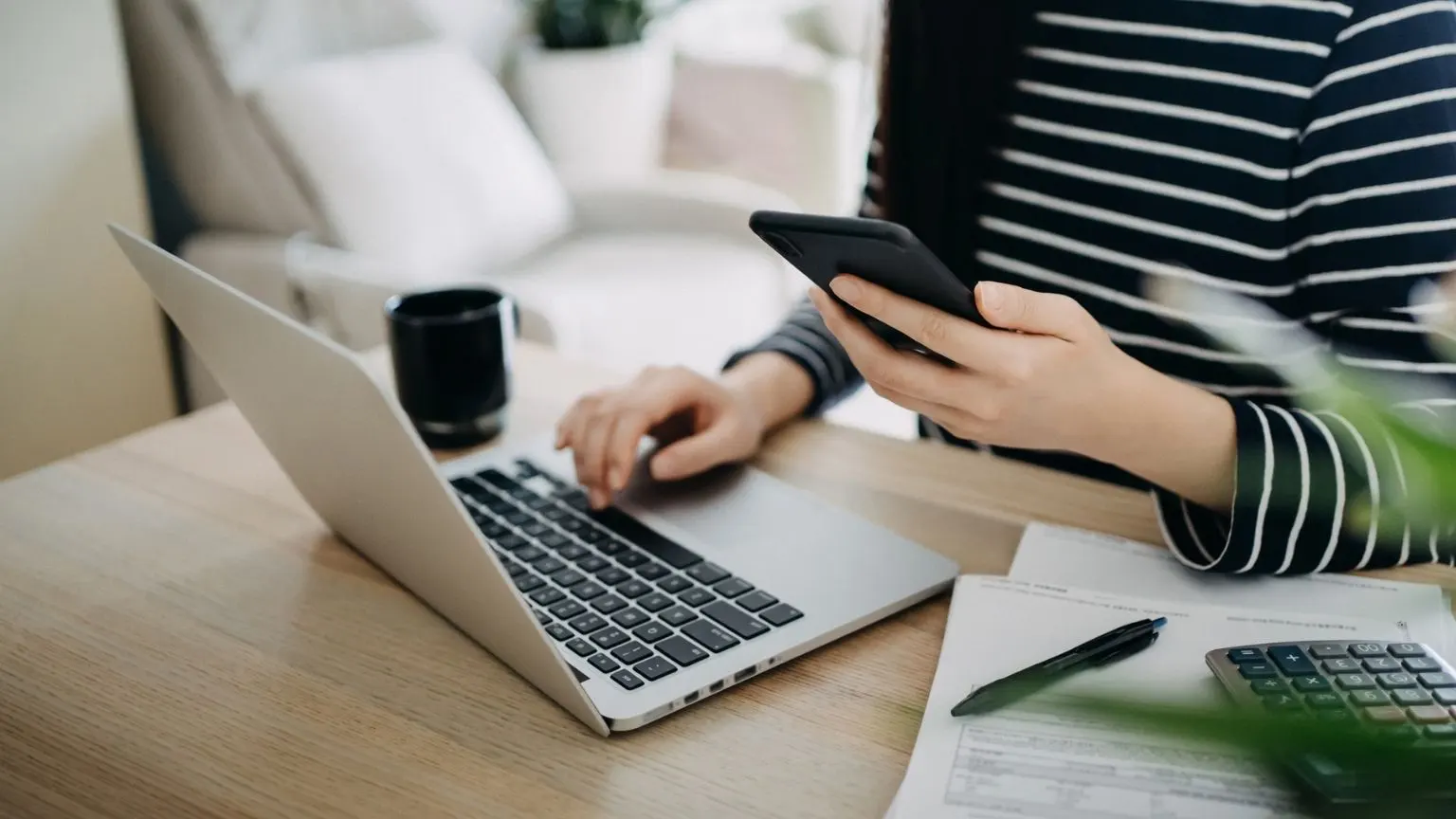 Young woman using laptop and smartphone