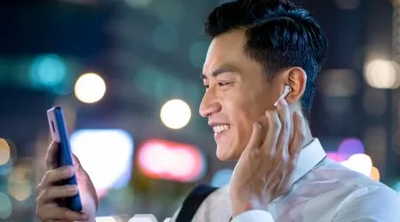 Man using phone with wireless earbuds