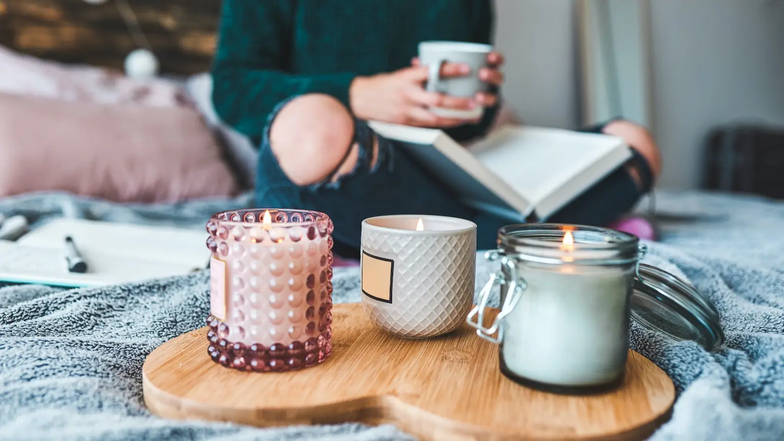 Cropped shot of an unrecognizable young woman relaxing with a book and a cup of coffee on her bed at home