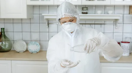 A woman in a hazmat suit applies an antibacterial antiseptic hand gel to disinfect and clean her hands during an outbreak of the influenza virus, the epidemic of coronavirus and infectious diseases. Covid-19.