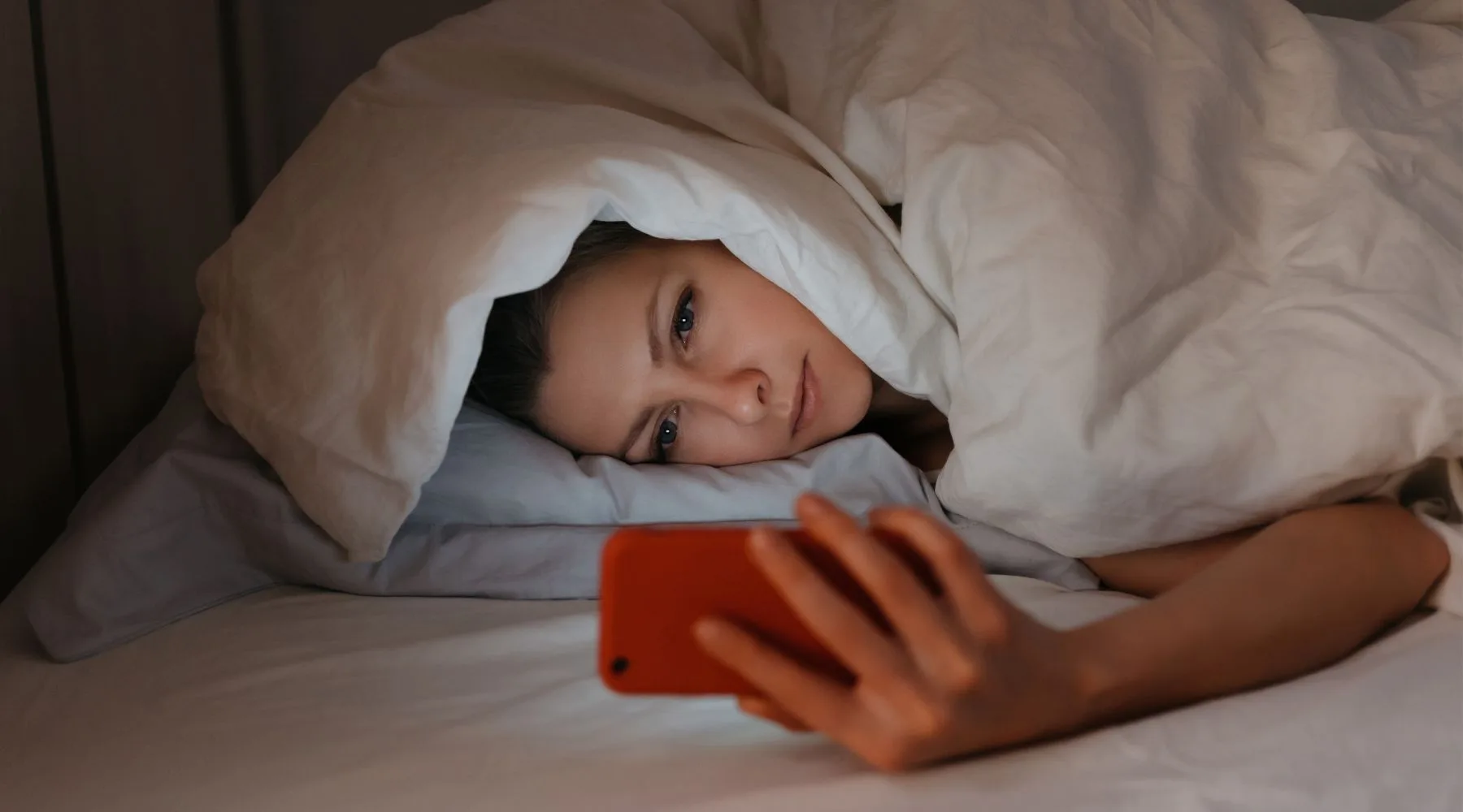 Image: Canva Woman on phone in bed
