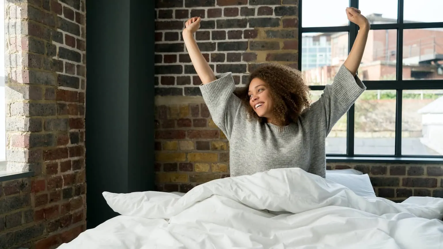 Happy woman stretching in bed